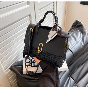 Detail of black woven leather handbag featuring a gold buckle and floral scarf handle