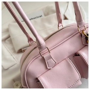 Detailed side view of pink leather handbag showing golden zippers and fine stitching