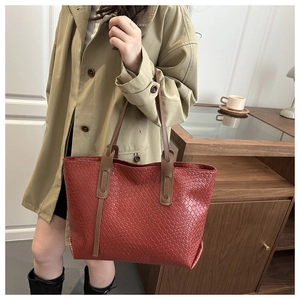 Dettaglio della borsa tote intrecciata rosso-marrone con manico in pelle marrone liscia