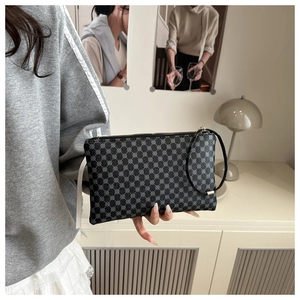 Detail of a patterned envelope clutch bag with leather wristlet in a modern interior setting