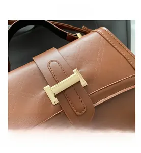 Detail of caramel leather shoulder bag with quilted stitching and gold rectangular buckle