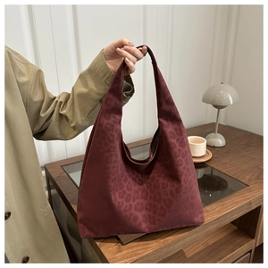 Close-up of a burgundy leopard print hobo bag with high-quality suede texture in a cozy setting