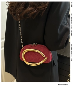 Close-up of burgundy velvet crossbody bag featuring round gold handles and chain strap