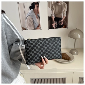 Detail of a chic black envelope clutch with grey M-pattern print and gold zipper