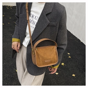 Detail of vintage brown suede tote bag with leather straps on an autumn street setting