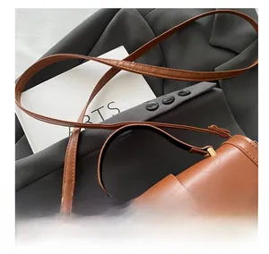 Detail showing the adjustable leather shoulder strap and golden metal buckle of the brown bag