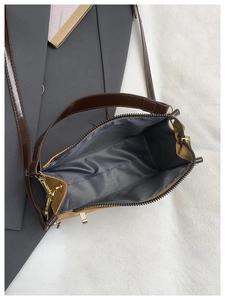 Detailed view of women's crossbody bag featuring metal zipper and dark fabric lining
