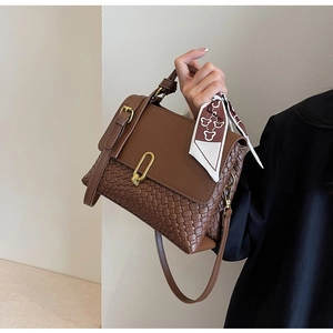 Detail of vintage brown leather bag with woven texture, metal buckle and silk scarf