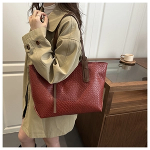 Borsa tote intrecciata bordeaux con tracolla lunga indossata da una modella in interno