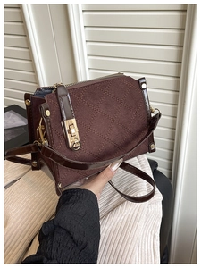 Detailed close-up of brown quilted handbag with classic plaid pattern and golden turn-lock