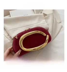 Detail view of burgundy frosted leather clutch with sculpted gold metal circular handle