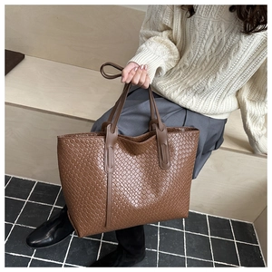 Dettaglio della borsa tote marrone scuro con trama intrecciata e manici in pelle