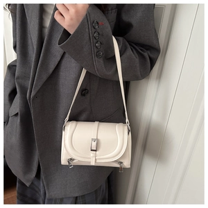 Creamy white leather crossbody bag detail worn with a dark grey blazer and plaid skirt