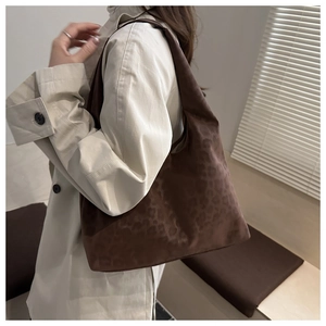 Detail of dark brown leopard embossed tote bag with soft texture on a shoulder