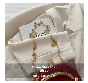 Close-up of golden metal chain strap on deep red velvet evening bag with handle