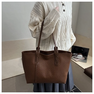 Dettaglio della borsa tote intrecciata marrone scuro con trama in pelle e manici rinforzati