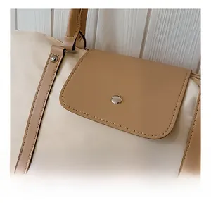 Detail view of the silver metal clasp and leather trim on a beige tote bag