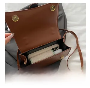 Internal storage view of brown quilted crossbody bag showing smartphone and essentials