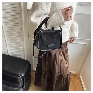 Minimalist black matte shoulder bag with gold hardware shown as a crossbody detail