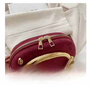 Detail of smooth double zipper closure on burgundy suede evening bag with gold handle