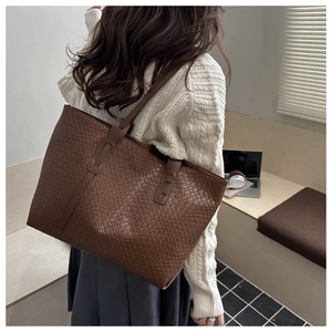Dettaglio della borsa tote in pelle intrecciata marrone scuro indossata dalla modella