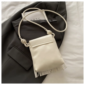 Gros plan du sac seau à franges blanc crème avec bandoulière en corde à nœuds élégante