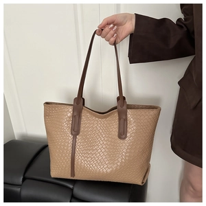 Dettaglio borsa tote intrecciata beige con manici marroni e finitura in pelle testurizzata