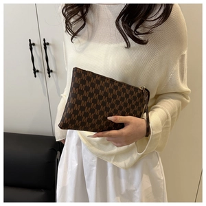 Detail of dark brown monogram clutch bag with wrist strap and gold zipper closure