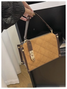 Detailed view of brown quilted suede handbag with gold lock and metal stud accents