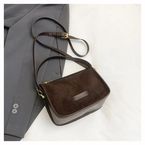 Detail of dark brown suede and smooth faux leather textures on a rectangular crossbody bag