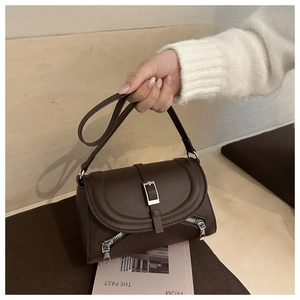 Detail of dark brown leather crossbody bag with silver zipper accents and chic strap