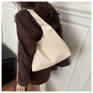 Detailed shoulder view of a minimalist cream-colored hobo tote bag in soft PU leather