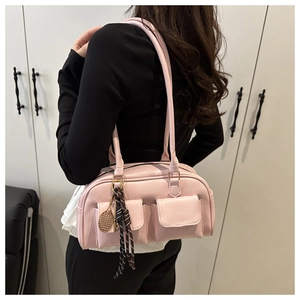 Detailed view of pink shoulder bag with dual exterior pockets and golden tennis racket charm