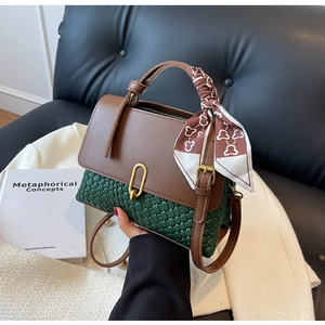 Detail of a two-tone woven handbag with gold U-buckle and silk scarf wrapped handle
