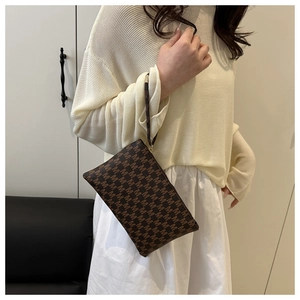 Detail of dark brown envelope clutch with M pattern monogram and matching wrist strap