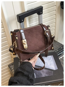 Close-up of brown velvet quilted handbag featuring golden lock and detailed stitching