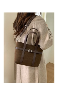 Detail view of a vintage brown tweed tote bag with leather straps and metallic buckle
