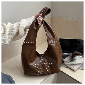 Detail of dark brown shoulder bag with silver star-shaped rivets and knotted handle