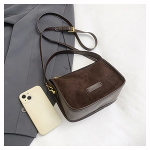Flat lay of brown suede shoulder bag with gold hardware and blazer on white background