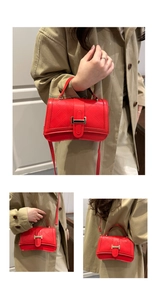Close-up of red quilted leather crossbody bag with golden H-shaped buckle on beige coat