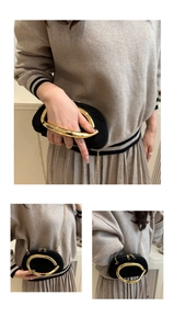 Detail of black velvet mini bag with gold round handle and metallic chain strap