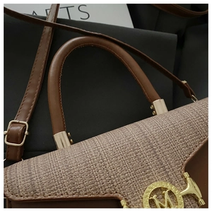 Detailaufnahme der braunen Leder- und Tweed-Handtasche mit goldener M-Logo-Schnalle
