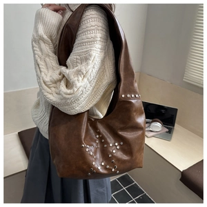 Close-up of a dark brown hobo tote bag featuring star-shaped silver rivet details