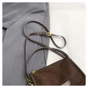 Close-up of vintage brown suede shoulder bag with golden metallic strap buckle