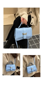 Detailed close-up of light blue quilted shoulder bag with gold metal buckle and leather handle