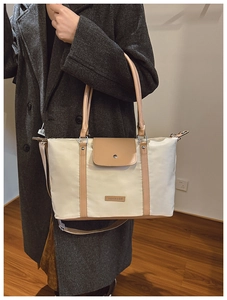 Close-up of beige and brown patchwork tote bag with fashion metal plate detail