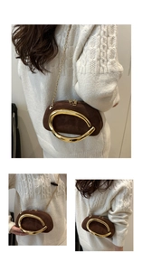 Detail of dark brown suede mini clutch with curved gold handle and chain shoulder strap