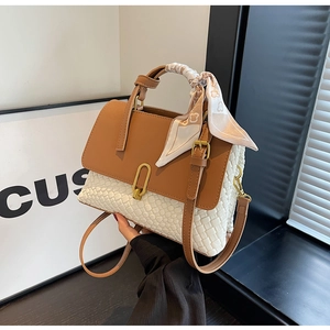 Detail of white woven bag with brown leather trim, gold lock and decorative silk scarf
