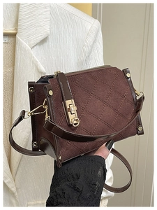 Detailed close-up of dark brown textured canvas crossbody bag with gold metallic buckle