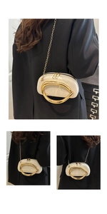 Detail of cream mini evening bag featuring large gold metal handle and chain strap